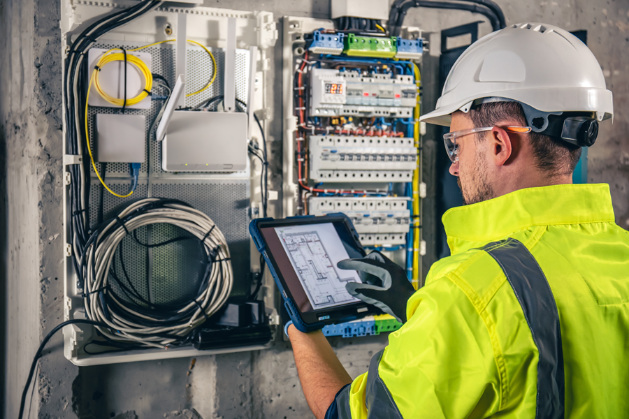 Elektro Junger Mann mit einem ipad vor einem Elektroschaltschrank