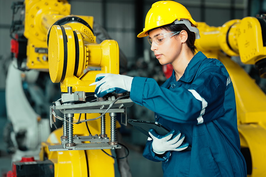 woman with yellow hat works at a machine